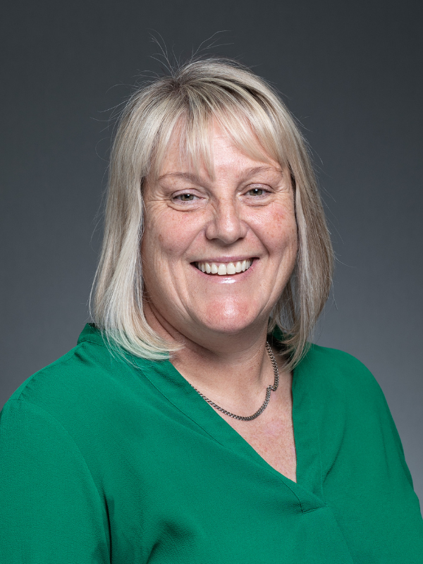 Lee-Anne Menzies smiles at the camera. She is wearing a green blouse.