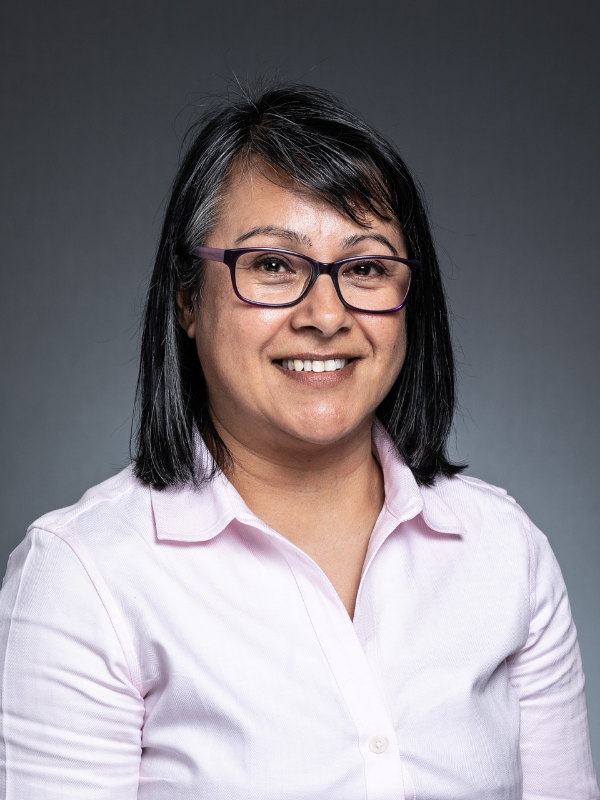 Image shows Councillor Shamin Akhtar. She is wearing a pink shirt and glasses and is sitting slightly side on, smiling at the camera.