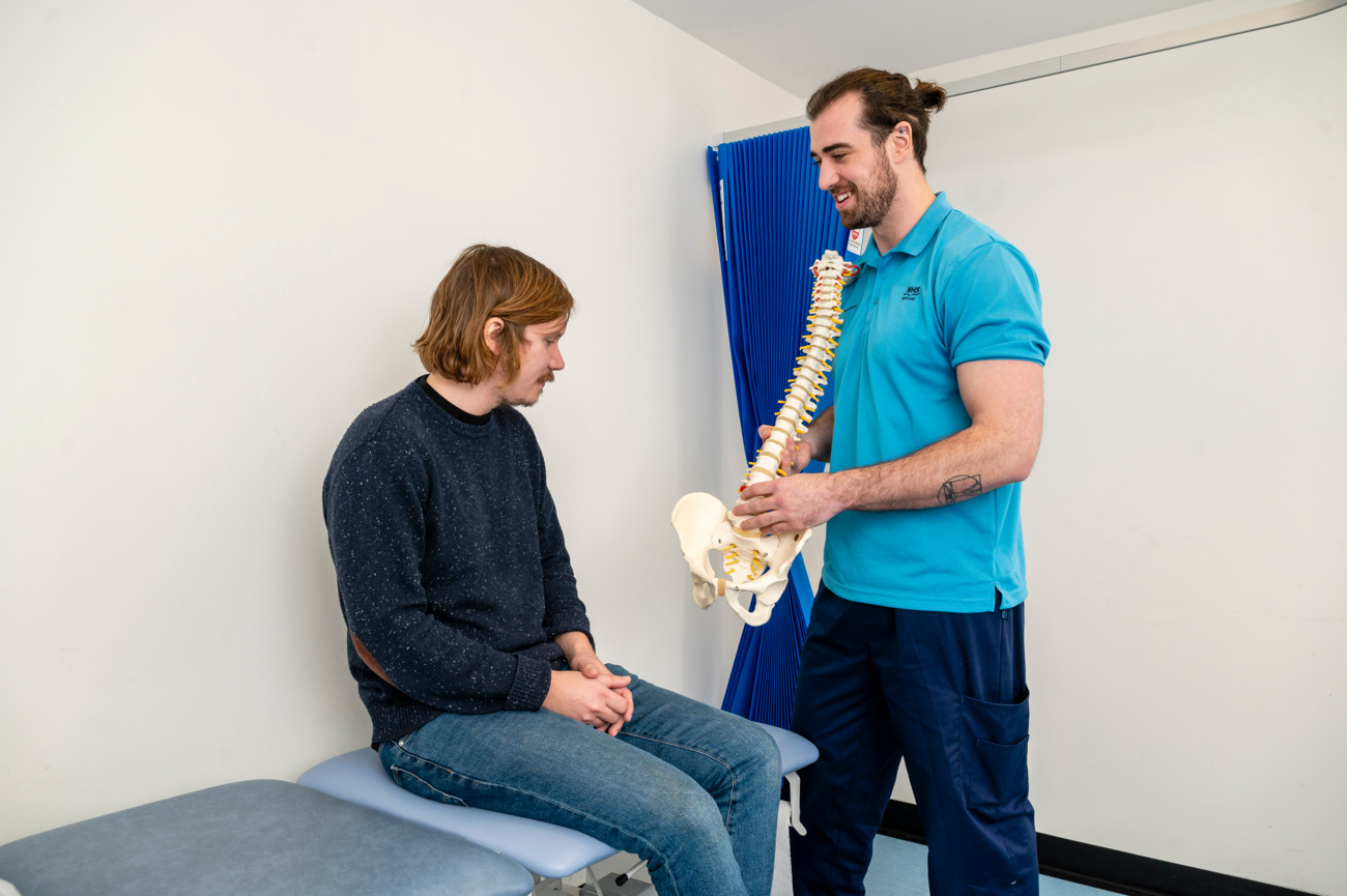 physiotherapist showing a spine model to a patient