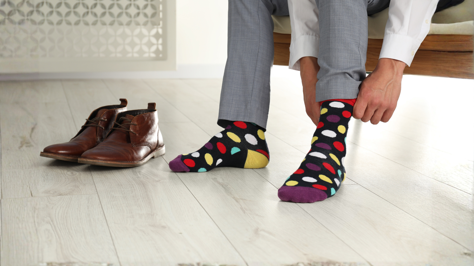 man sitting on sofa putting on socks and shoes
