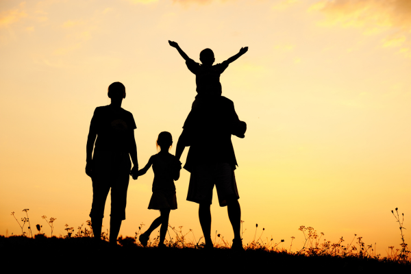 Family of four silhouetted against an orange sky.