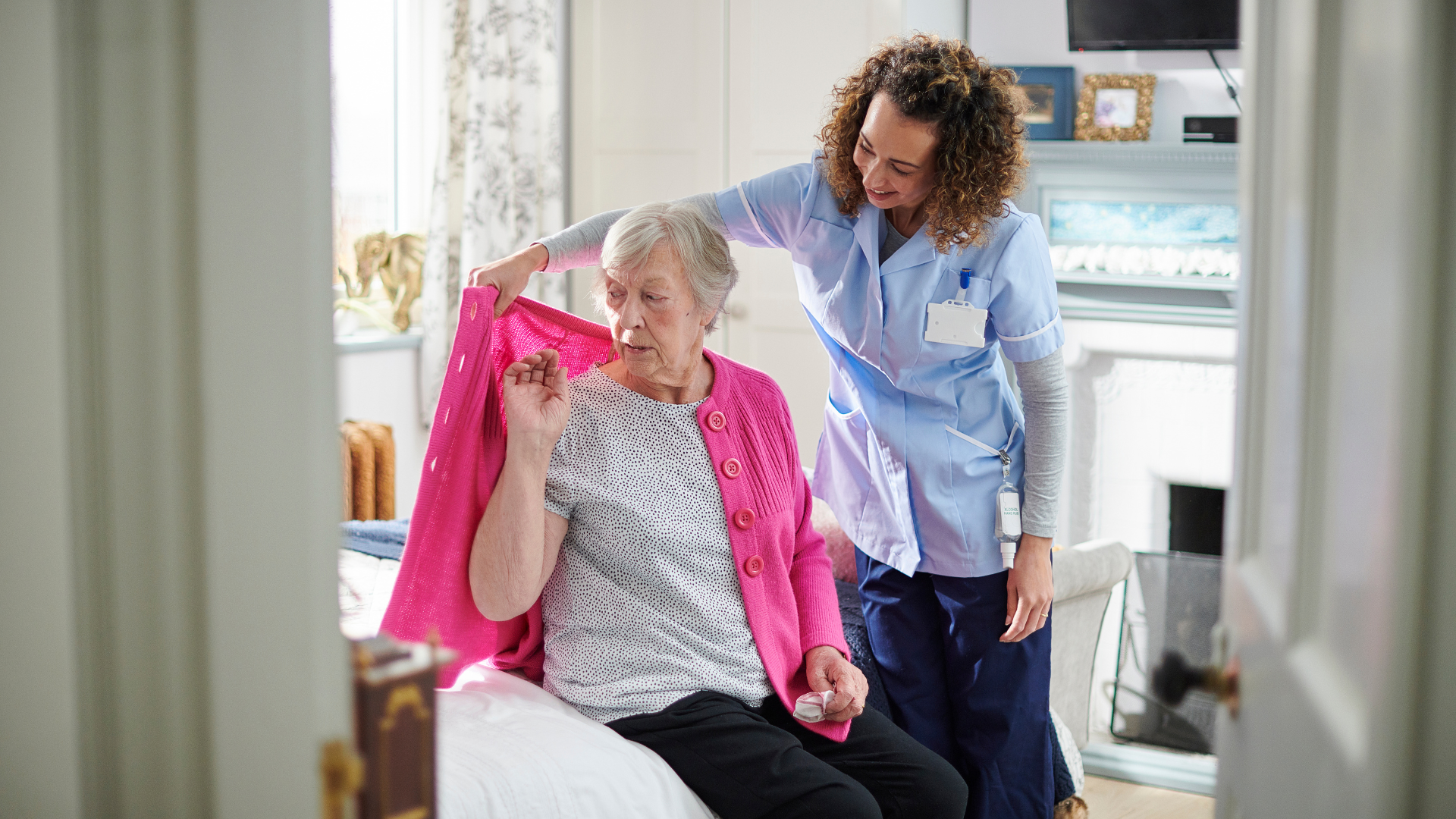 carer is helping a woman put on a cardigan