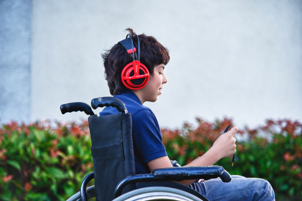 Teenager in wheelchair listening to music on headphones