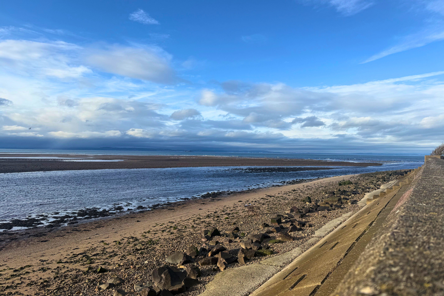 A view out to sea at Longniddry with a blue sky and fluffy white clouds.