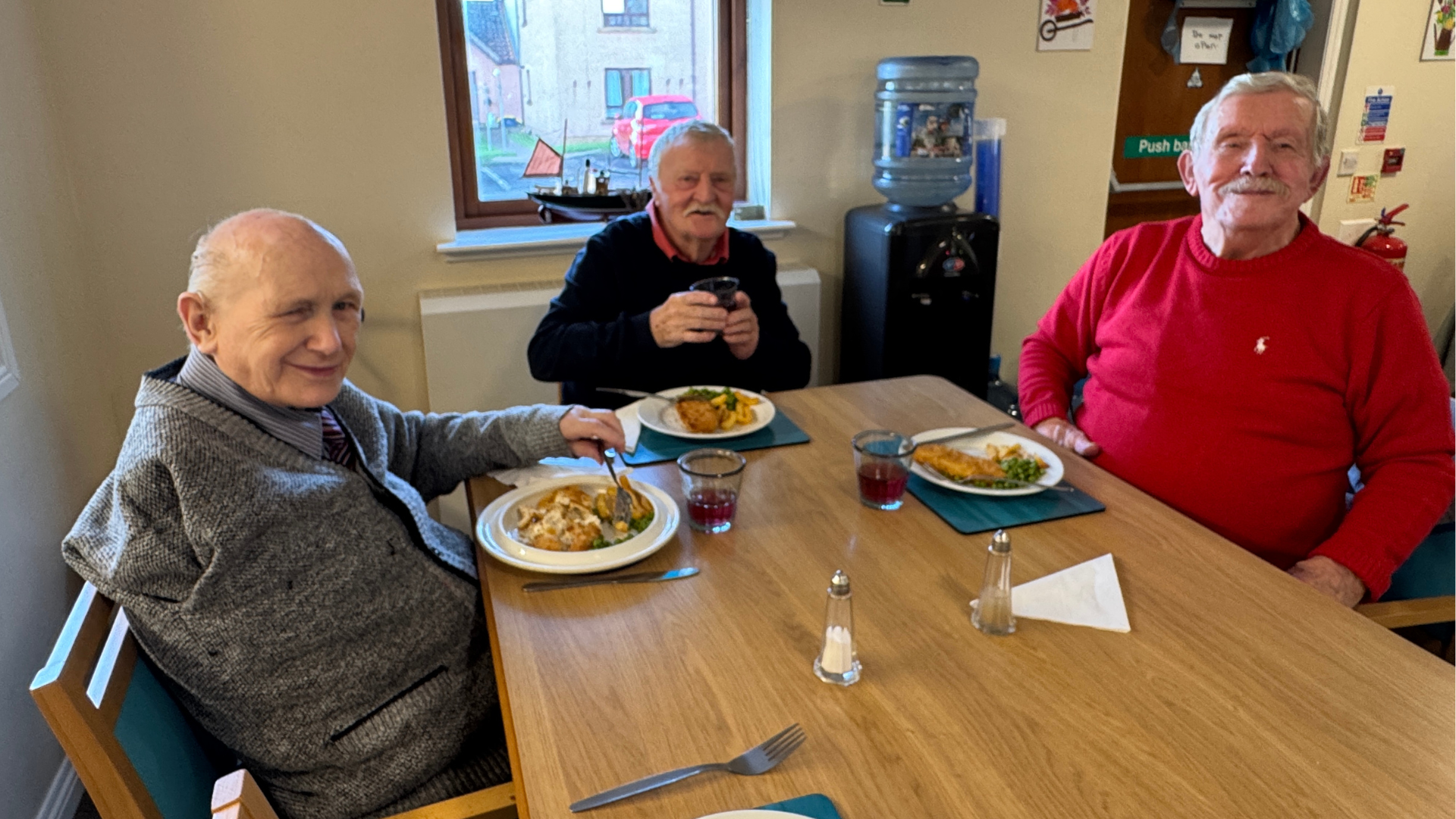 Three men enjoying fish and chips at a lunch club