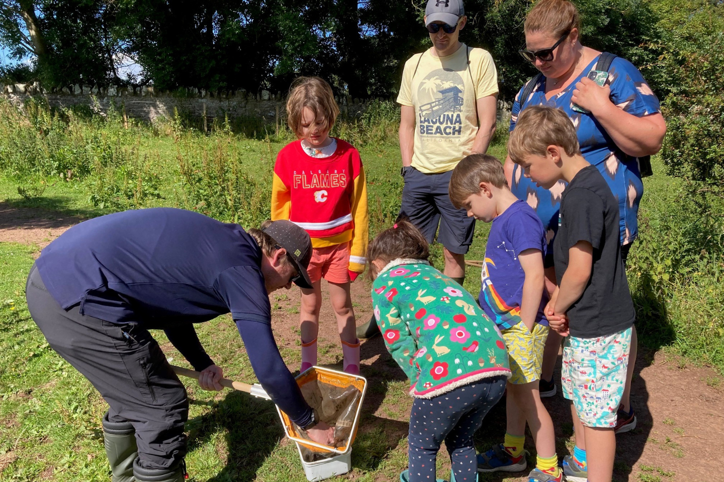 Ranger demonstrating specimen collection to a group of children and their parents.