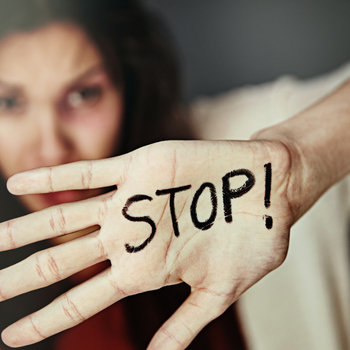 Woman holding up hand with stop written on it