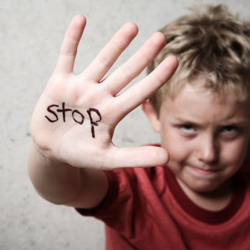 child holding up hand with stop written on it
