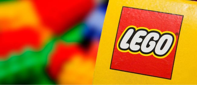 Image shows the Lego logo with blurred Lego bricks in the background