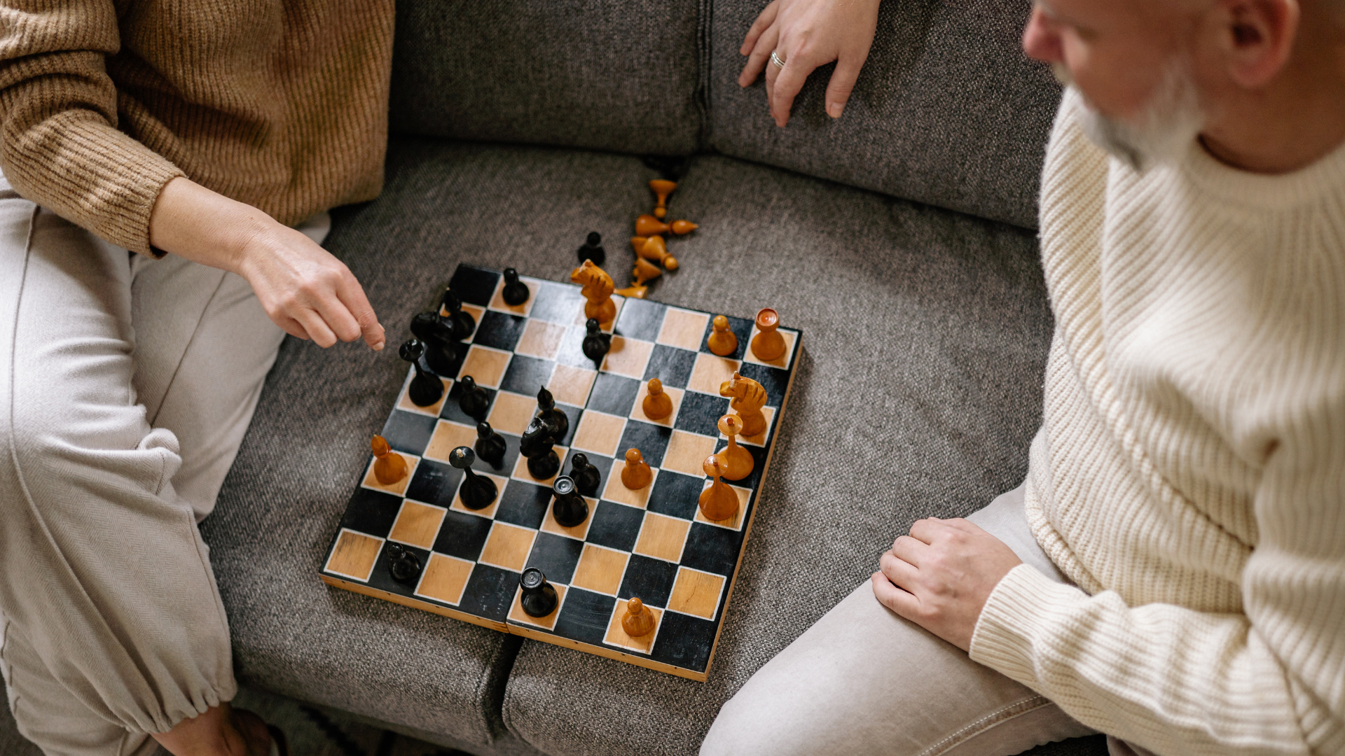 two people playing chess on a sofa