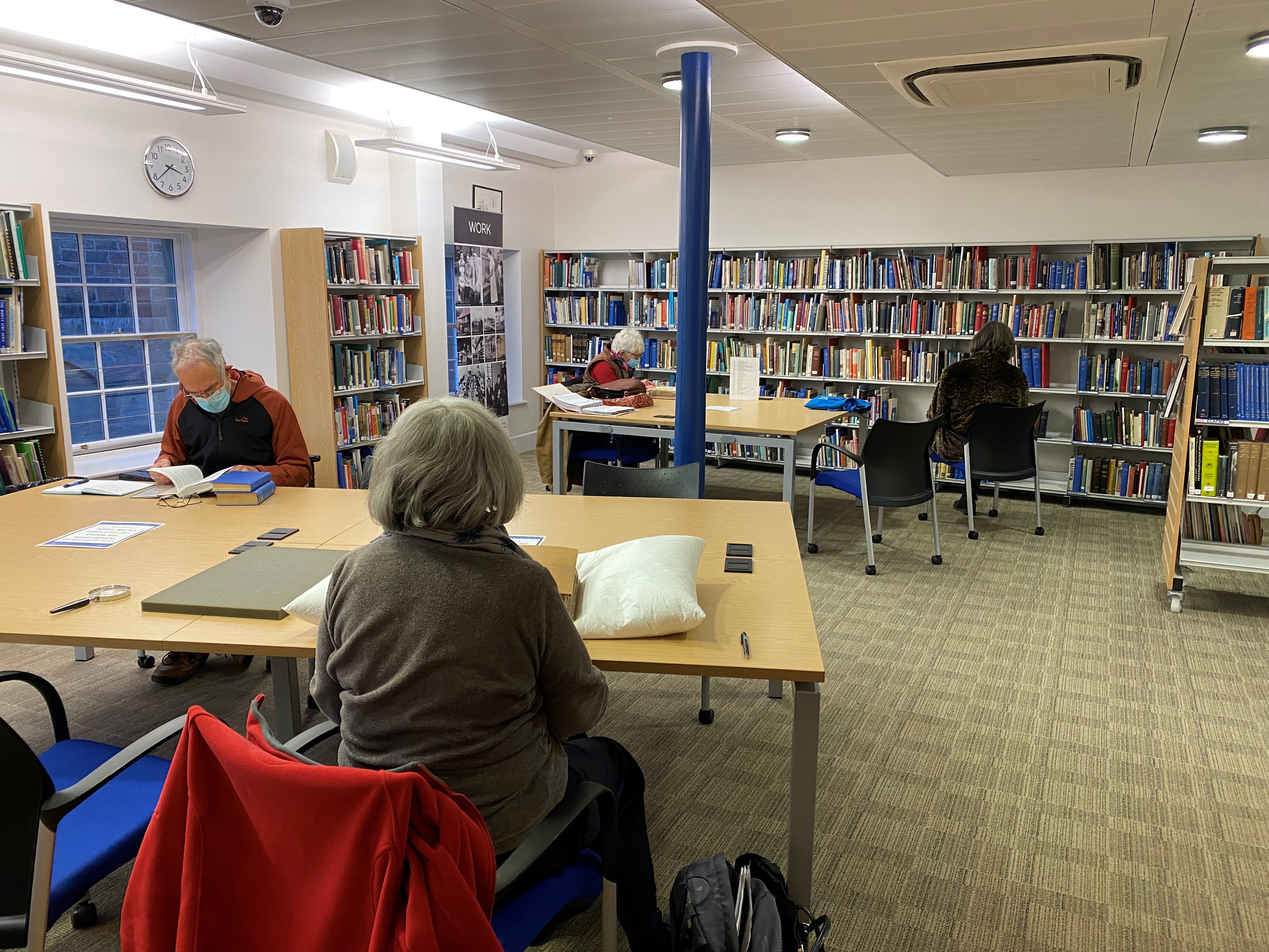 Photo of people sitting at desks in a room filled with bookshelves