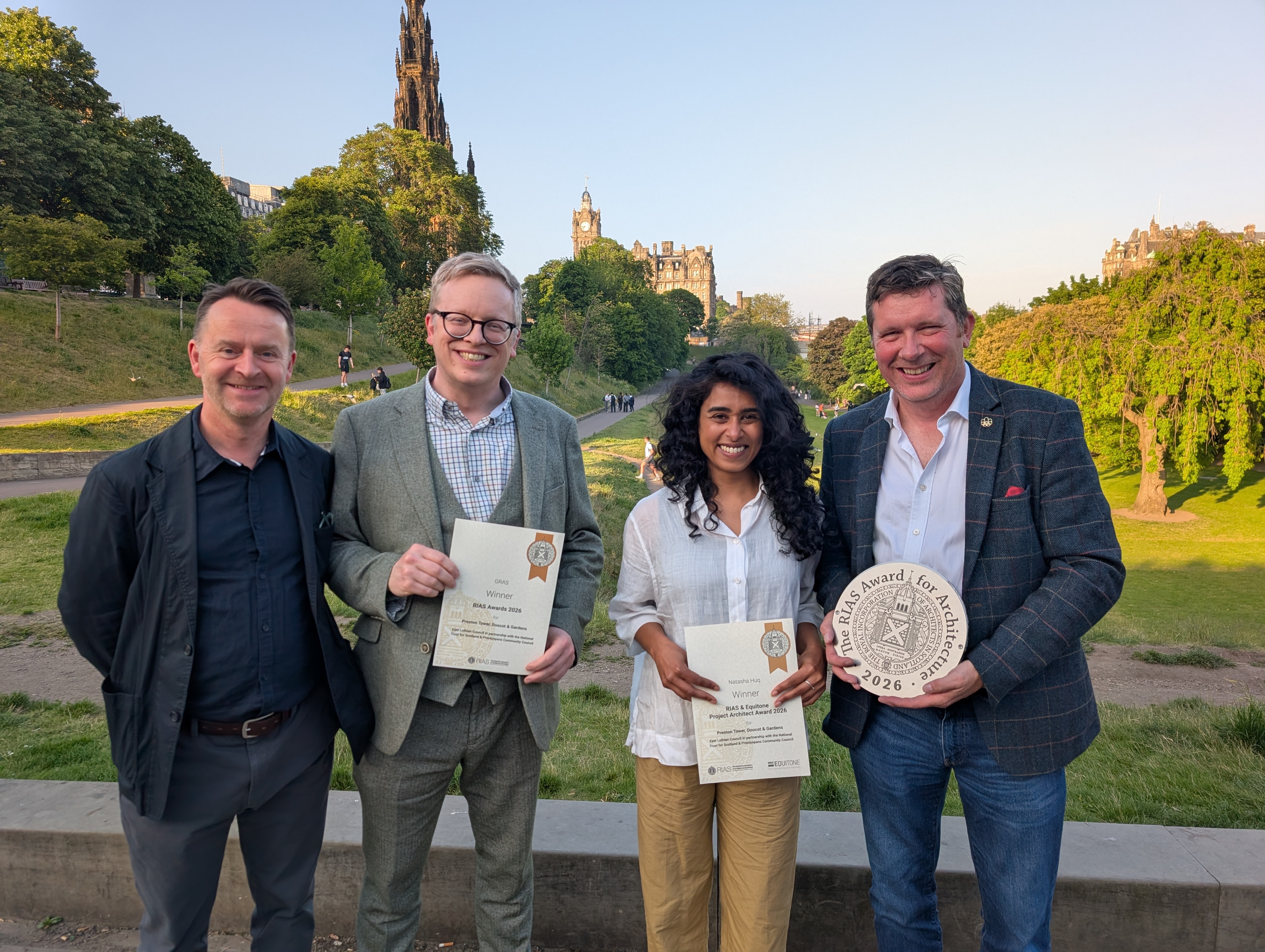 Four people with award plaques and certificates