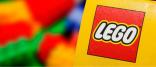 Image shows the Lego logo with blurred Lego bricks in the background